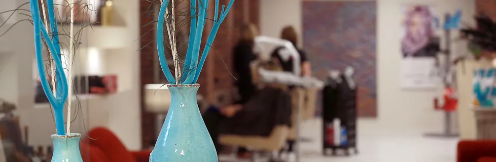 Türkise Vase im Salon, dahinter Kundinnen am Waschplatz